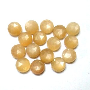 May include: A collection of 16 round, faceted, light yellow gemstone cabochons. The stones have a slightly iridescent sheen.
