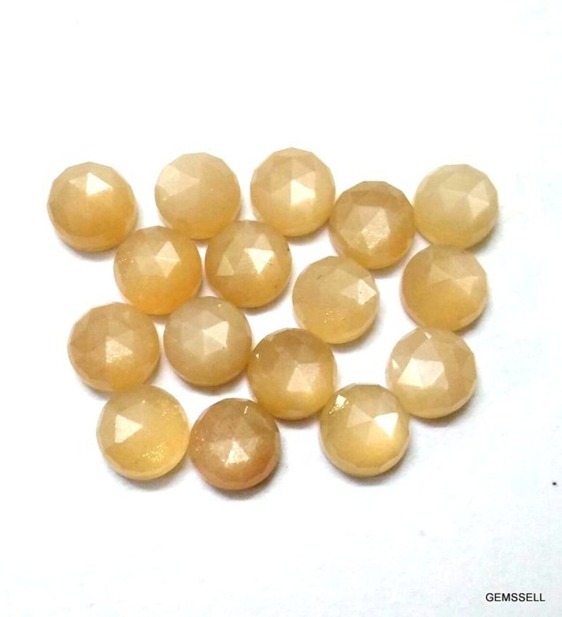 May include: A collection of 16 round, faceted, light yellow gemstone cabochons. The stones have a slightly iridescent sheen.