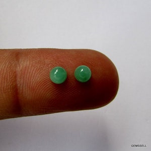 Puede incluir: Dos piedras preciosas redondas de color verde en un dedo.