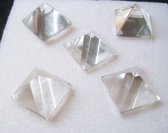 May include: Five clear quartz crystal pyramids on a white background. The pyramids are all the same size and shape, and they are arranged in a semi-circle.