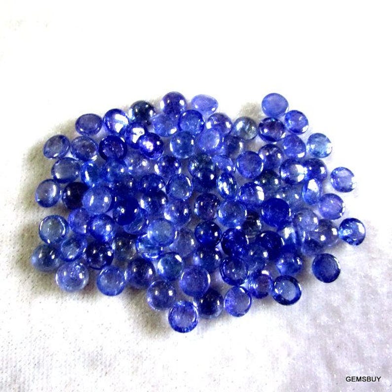 May include: A pile of round, blue gemstones. The gemstones are smooth and shiny, and they are all about the same size.