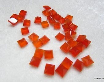 May include: A collection of 25 orange carnelian gemstone square cabochons. The stones are faceted and have a polished finish.