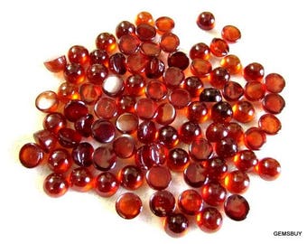 May include: A large group of round, red gemstone cabochons. The cabochons are smooth and polished, with a glossy finish.