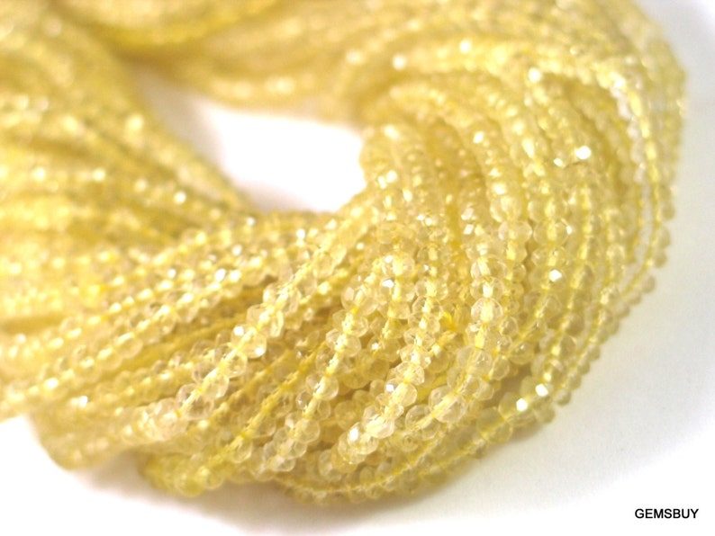May include: A strand of yellow faceted gemstone beads. The beads are small and have a translucent appearance.