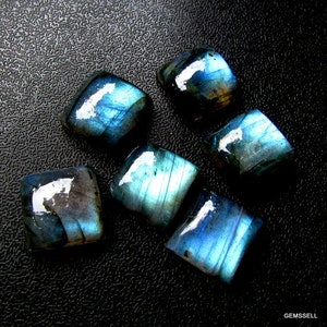 May include: Six iridescent blue labradorite gemstone cabochons, cut into square shapes, with a dark blue and black background.