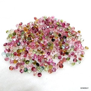 Puede incluir: Un mont&oacute;n grande de piedras preciosas redondas y facetadas en varios tonos de rosa, verde y marr&oacute;n. Las piedras preciosas est&aacute;n esparcidas sobre una superficie blanca.