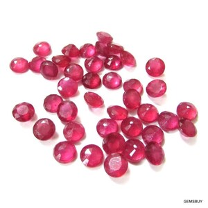 Pode incluir: Uma coleção de 30 pedras preciosas de rubi redondas e facetadas. Os rubis são de cor vermelha profunda e têm um acabamento polido.