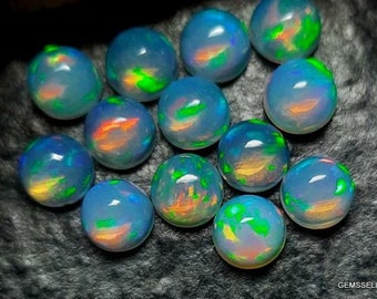 May include: A collection of 14 round, iridescent opal cabochons. The opals are a pale blue-grey color with flashes of green, orange, and yellow.