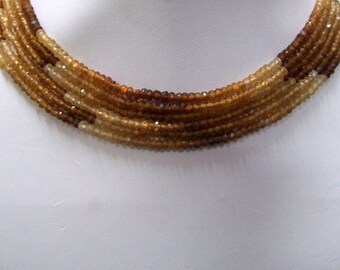 May include: A multi-strand necklace made of brown and light brown faceted gemstone beads.