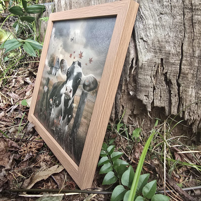 May include: A framed painting of a black and white cow standing in a field with autumn leaves in the air. The cow is looking directly at the viewer.