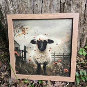 May include: A framed print of a black and white sheep wearing a crown of flowers. The sheep is standing in a field with a fence and a farmhouse in the background. The image has a vintage, faded look.