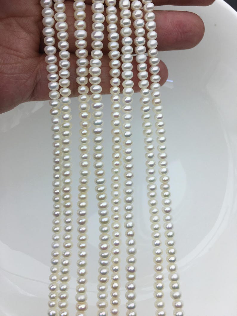 May include: Multiple strands of small, white pearls are shown against a white backdrop. The pearls are round and strung together, likely for necklaces or other jewellery. The pearls have a shiny appearance, reflecting light.