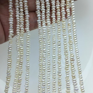 May include: Multiple strands of small, off-white, irregularly shaped freshwater pearls. Each strand features a continuous string of tiny, textured, organic-looking beads with a lustrous finish, arranged vertically in a parallel formation.