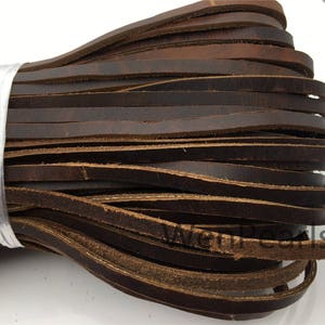 Op de afbeelding: Een bundel bruin lederen koord, ongeveer 6 mm breed, is samen gewikkeld met een doorzichtig plastic band. Het lederen koord is zacht en soepel, en het is perfect voor knutselprojecten.