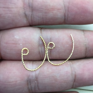 May include: A pair of gold-colored hoop earrings with a twisted rope design.