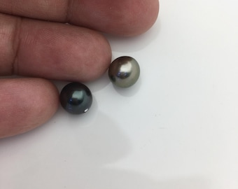 May include: Two spherical pearls with a smooth, lustrous finish. One pearl is a deep, dark charcoal gray, while the other is a lighter, metallic silver-gray. Both items exhibit a reflective surface quality and are round in shape.