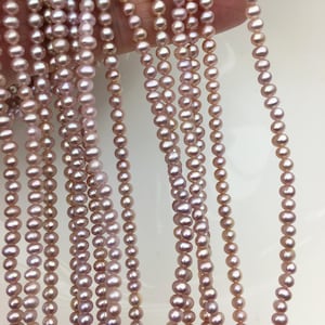 May include: Multiple strands of pink freshwater pearls. The pearls vary in size and have a soft, lustrous sheen, with colours ranging from pale pink to rose. The pearls are strung together, creating a delicate and elegant appearance, ideal for jewellery making or crafting.