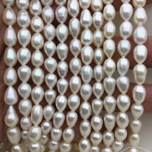 May include: A strand of white freshwater pearls, each pearl is a teardrop shape with a smooth, lustrous surface.