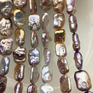 May include: Strands of iridescent, baroque pearls in shades of gold, lavender, and cream. The irregular shapes of the pearls create a unique, organic aesthetic. The pearls are strung together, ready for jewelry making.
