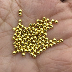 Puede incluir: Un montón grande de pequeñas cuentas doradas brillantes. Las cuentas son redondas y tienen una superficie lisa.