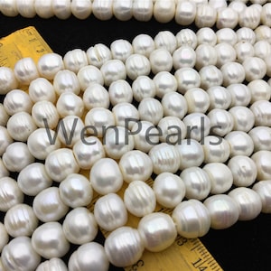 May include: A strand of white freshwater pearls, each pearl is round and smooth with a slight iridescent sheen. The pearls are arranged in a single row and are approximately 8-9mm in size. The pearls are displayed on a yellow measuring tape.