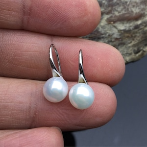 May include: A pair of silver dangle earrings with white pearl drops.