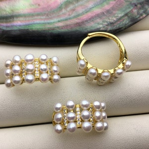 Op de afbeelding: Drie gouden ringen met witte parel accenten. De ringen zijn bezet met kleine witte parels in een rechthoekige en ronde vorm.