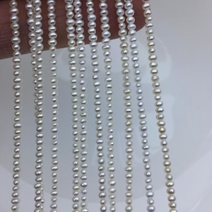 May include: A strand of white freshwater pearls, strung on a thin thread. The pearls are small and uniform in size, with a smooth, glossy finish.