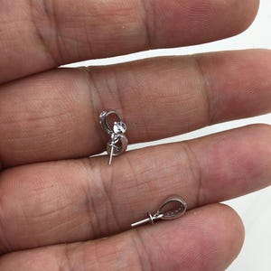 May include: Two silver-toned pendant bails with a clear crystal accent. The bails have a loop at the top and a pin at the bottom.