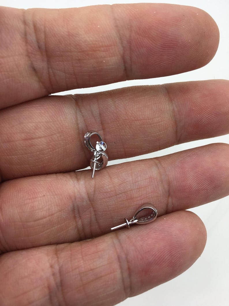 May include: Two silver-toned pendant bails with a clear crystal accent. The bails have a loop at the top and a pin at the bottom.