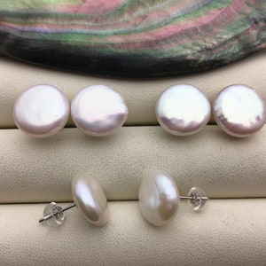 May include: A set of six white pearl earrings. The pearls are round and have a smooth, glossy finish. The earrings are made with silver posts and backs.