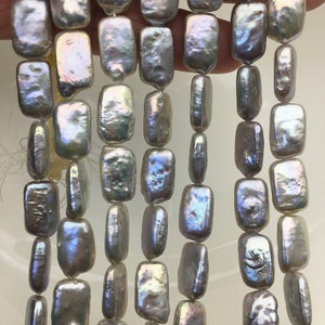 May include: A strand of iridescent white freshwater pearls, each pearl is rectangular and has a slightly irregular shape.