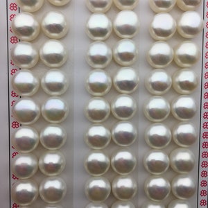 Puede incluir: Una tarjeta blanca con las palabras "High Fashion" impresas en ella. La tarjeta tiene 3 filas de 9 perlas blancas, cada perla mide aproximadamente 1 cm de diámetro.
