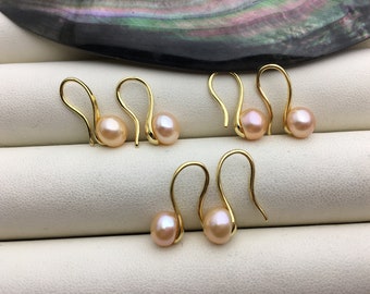 May include: A set of four gold-toned earrings with pink pearl accents. Each earring features a simple, curved hook design.