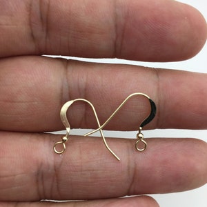 May include: A pair of gold-toned earring hooks with a small ball at the end of each hook.