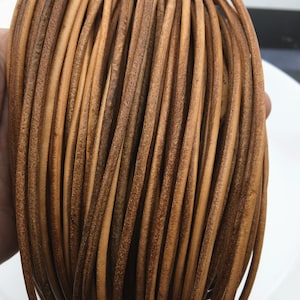 May include: A close-up of a bundle of brown leather cord. The cord is smooth and has a slightly textured surface.