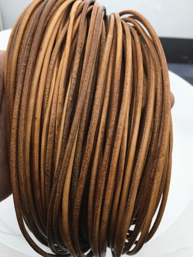 May include: A close-up of a bundle of brown leather cord. The cord is smooth and has a slightly textured surface.