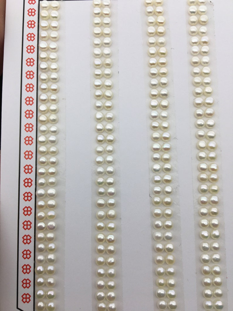 Puede incluir: Cuatro filas de perlas blancas dispuestas verticalmente sobre un fondo blanco. Cada fila contiene 20 perlas.