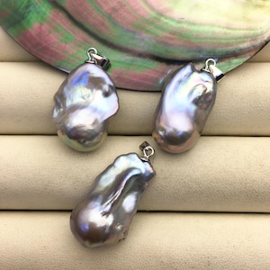 Könnte beinhalten: Drei irisierende graue Barockperlen-Anhänger mit silbernen Ösen. Die Perlen sind unregelmäßig geformt und haben einen Perlmuttglanz.