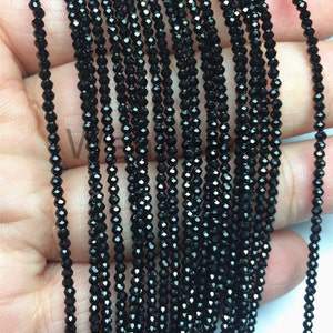 Puede incluir: Una hebra de cuentas de piedras preciosas facetadas negras. Las cuentas son pequeñas y de tamaño uniforme, y están enhebradas en un hilo transparente. Las cuentas están dispuestas en línea recta y todas están orientadas en la misma dirección.