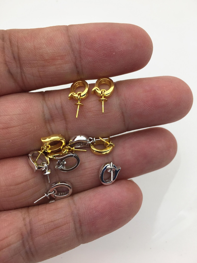 Pu&ograve; includere: Una collezione di componenti per orecchini in oro e argento. I componenti includono piccoli orecchini a cerchio con un perno per attaccare un ciondolo o una perla. Gli orecchini dorati sono di un giallo brillante, mentre quelli argentati hanno una finitura lucida.