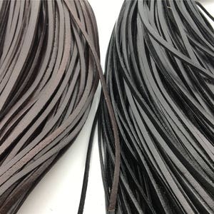 May include: Two bundles of leather cord, one brown and one black. The cords are flat and have a smooth texture.