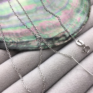 May include: A silver chain necklace with a lobster clasp closure. The chain is delicate and has a simple design.