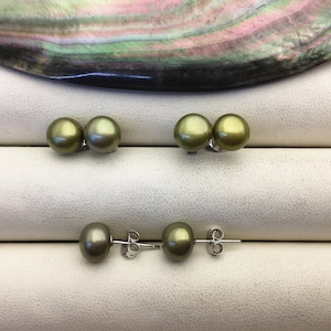 May include: A pair of green pearl earrings with silver posts. The earrings are displayed on a white surface.