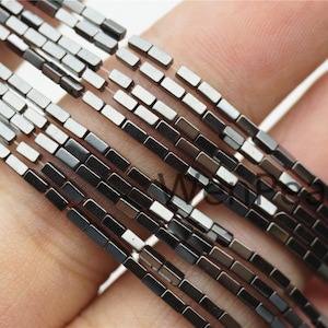 Peut inclure: Un brin de perles d'hématite noire, chaque perle est de forme rectangulaire. Les perles sont enfilées sur un cordon élastique transparent.