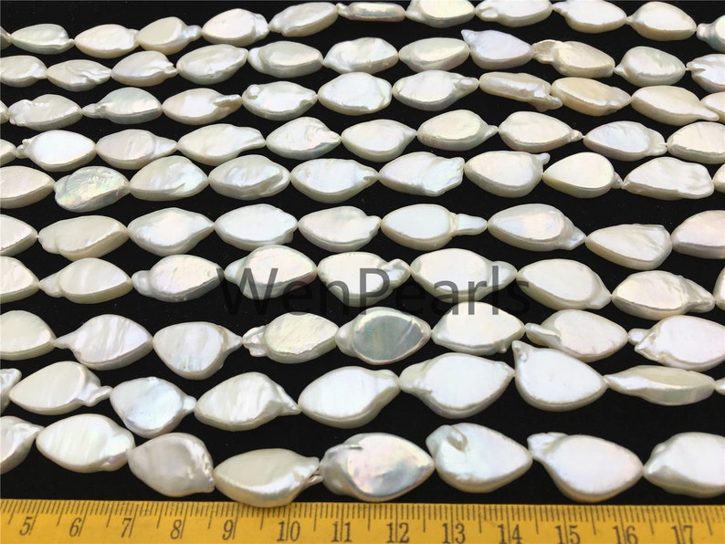 May include: A strand of white, pearlescent, oval-shaped beads. The beads are arranged in rows and are approximately 1/2 inch in length. The beads are strung on a clear thread.