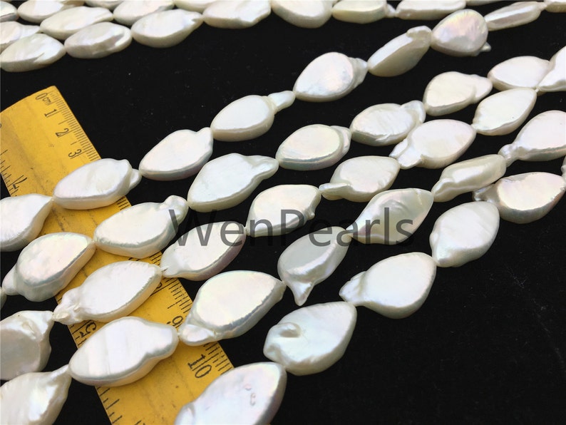 May include: A strand of white freshwater pearls with a slightly irregular, teardrop shape. The pearls are strung on a clear thread and are approximately 10mm in size.