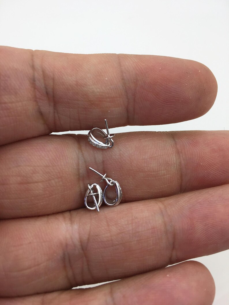 May include: Two silver-toned jewelry clasps with a small row of clear stones around the edge. The clasps are open and ready to be attached to a necklace or bracelet.