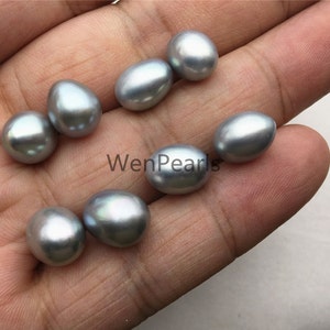 May include: A collection of eight oval-shaped, silver-grey pearls. The pearls are smooth and lustrous.