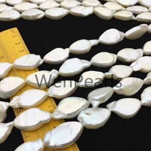 May include: A strand of white freshwater pearls with a slightly irregular, oval shape. The pearls are strung on a clear thread and are arranged in a loose, flowing pattern. The pearls are approximately 10mm in size.